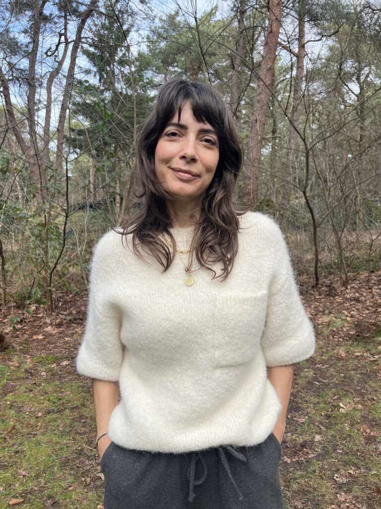 Portrait of Daphne Maierna in a cream jumper in the woods